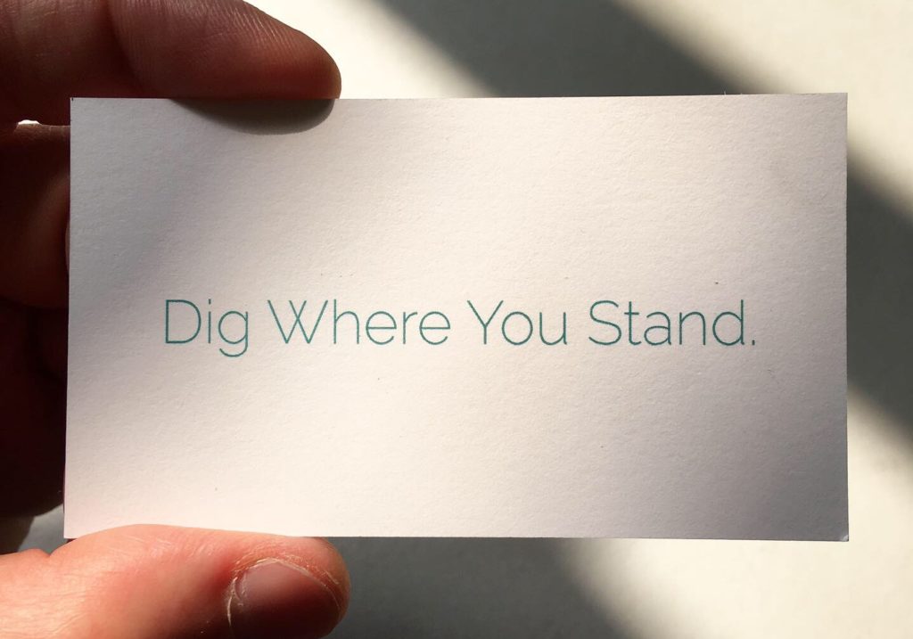 A small card reads "Dig Where You Stand"